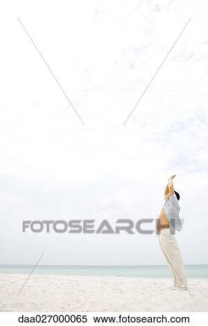 Man standing in sun salutation pose on beach, side view View Large Photo Image Stock Photography - Man standing in sun salutation pose on beach, side view. Fotosearch