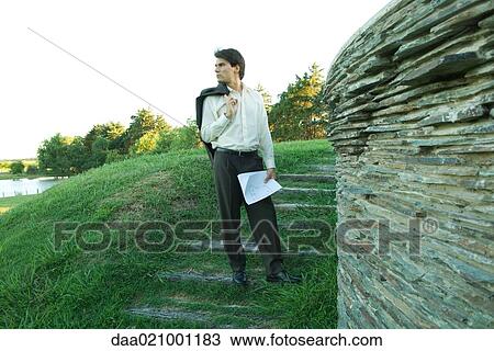 Man standing near stone wall, holding blueprints View Large Photo Image Stock Image - Man standing near stone wall, holding blueprints. Fotosearch