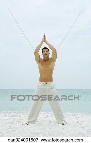 Man standing on beach, doing yoga, full length View Large Photo Image Stock Photo - Man standing on beach, doing yoga, full length. Fotosearch