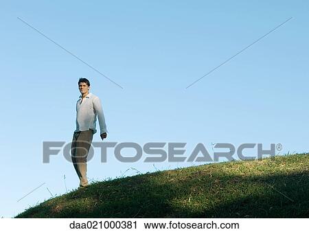 Man standing on hill, low angle view View Large Photo Image Stock Image - Man standing on hill, low angle view. Fotosearch