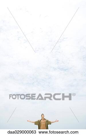 Man standing outdoors, arms out, head back, mid-distance View Large Photo Image Stock Image - Man standing outdoors, arms out, head back, mid-distance. Fotosearch