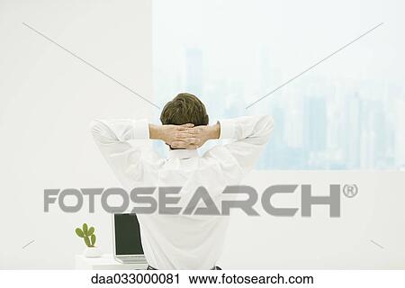 Man stretching with hands behind his head, laptop and cactus on desk, rear view View Large Photo Image Stock Image - Man stretching with hands behind his head, laptop and cactus on desk, rear view. Fotosearch