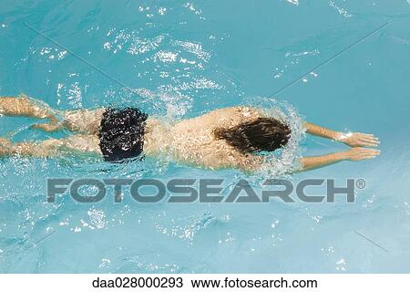 Stock Image - Man swimming in pool, high angle view. Fotosearch