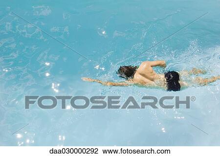 Stock Image - Man swimming in pool, high angle view. Fotosearch