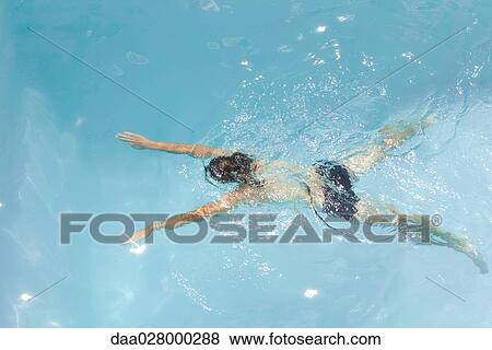 Stock Photo - Man swimming in pool, rear view, high angle. Fotosearch