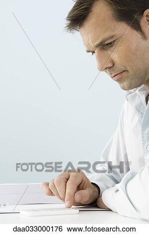 Man using calculator, sitting at table, side view View Large Photo Image Stock Photograph - Man using calculator, sitting at table, side view. Fotosearch