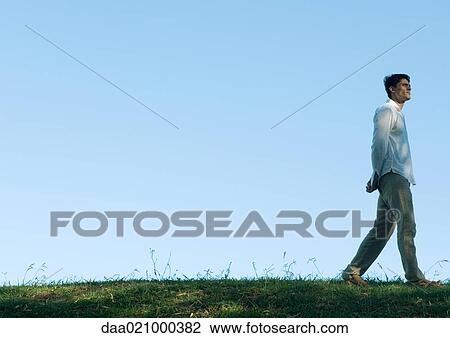 Man walking across grass, low angle view View Large Photo Image Stock Image - Man walking across grass, low angle view. Fotosearch
