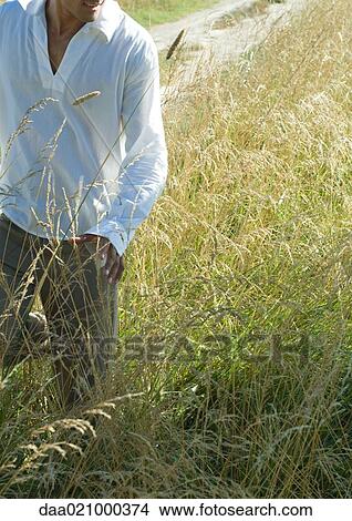 Picture - Man walking through field, neck down. Fotosearch