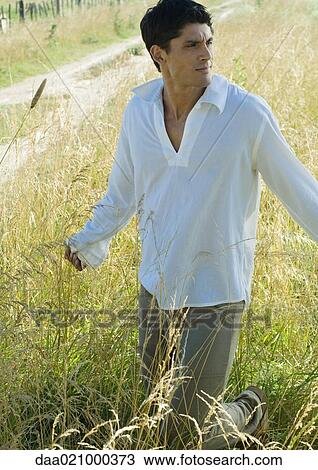 Man walking through field View Large Photo Image Stock Image - Man walking through field. Fotosearch
