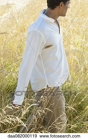 Man walking through field View Large Photo Image Stock Photo - Man walking through field. Fotosearch