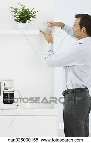 Man watering plant with plastic water bottle View Large Photo Image Stock Photo - Man watering plant with plastic water bottle. Fotosearch