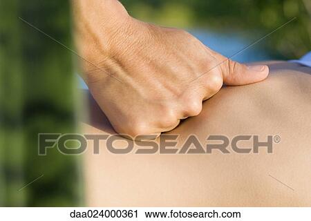 Stock Image - Massage therapist's hand on patient's abdomen, close-up. Fotosearch