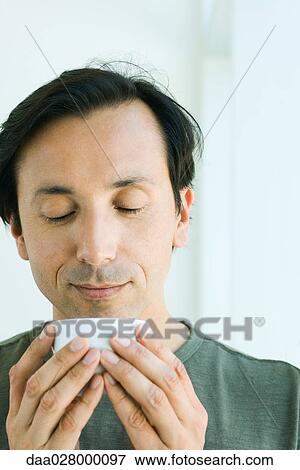 Mature man holding cup up to face, looking down, smiling View Large Photo Image Stock Photo - Mature man holding cup up to face, looking down, smiling. Fotosearch