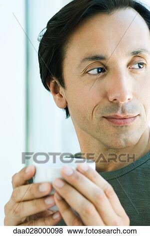 Mature man holding up cup, looking away, smiling View Large Photo Image Stock Photo - Mature man holding up cup, looking away, smiling. Fotosearch