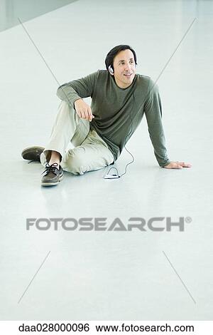 Mature man sitting on floor, listening to MP3 player, full length View Large Photo Image Stock Photograph - Mature man sitting on floor, listening to MP3 player, full length. Fotosearch