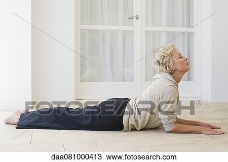Stock Image - Mature woman doing cobra pose with eyes closed. Fotosearch
