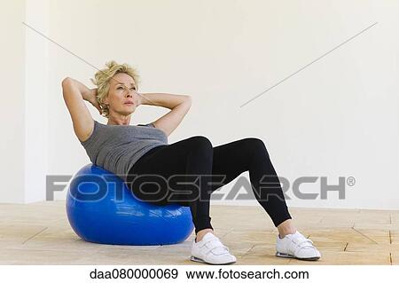 Stock Photo - Mature woman doing sit-ups on fitness ball. Fotosearch