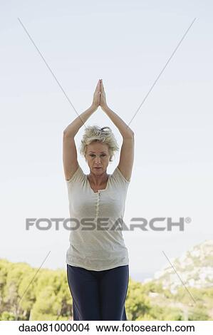 Picture - Mature woman doing sun salutation pose. Fotosearch