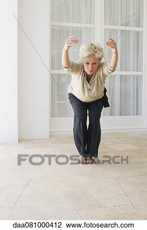 Stock Image - Mature woman doing yoga chair pose. Fotosearch