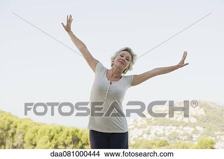 Mature woman exercising with arms outstretched View Large Photo Image Picture - Mature woman exercising with arms outstretched. Fotosearch