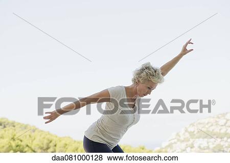 Mature woman exercising with arms outstretched View Large Photo Image Stock Photo - Mature woman exercising with arms outstretched. Fotosearch