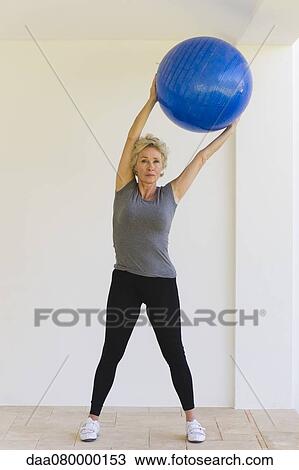 Mature woman holding up fitness ball View Large Photo Image Stock Image - Mature woman holding up fitness ball. Fotosearch