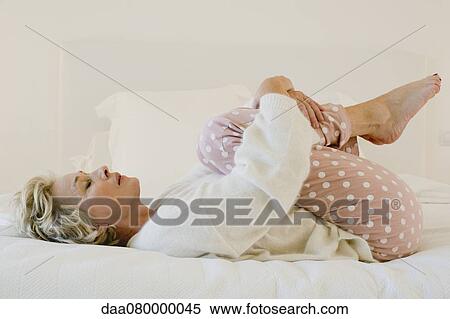 Mature woman lying on bed in fetal position View Large Photo Image Stock Photography - Mature woman lying on bed in fetal position. Fotosearch