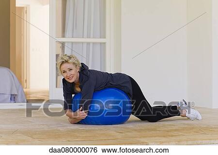 Mature woman lying on stomach on fitness ball View Large Photo Image Stock Photograph - Mature woman lying on stomach on fitness ball. Fotosearch