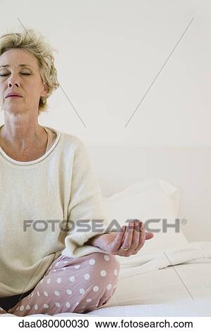 Mature woman meditating on bed, cropped View Large Photo Image Stock Image - Mature woman meditating on bed, cropped. Fotosearch