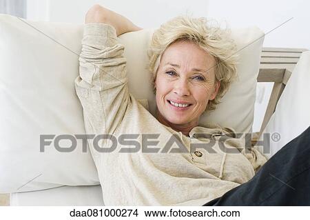 Picture - Mature woman relaxing on sofa, portrait. Fotosearch
