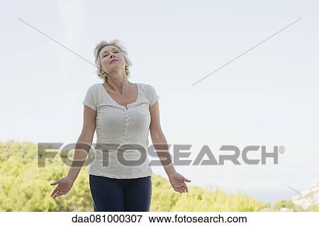 Mature woman rolling neck outdoors with eyes closed View Large Photo Image Stock Photo - Mature woman rolling neck outdoors with eyes closed. Fotosearch