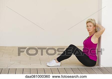 Mature woman sitting against wall with arms behind back View Large Photo Image Stock Image - Mature woman sitting against wall with arms behind back. Fotosearch