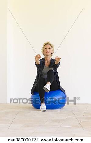 Mature woman sitting on fitness ball with arms out and one leg up View Large Photo Image Stock Image - Mature woman sitting on fitness ball with arms out and one leg up. Fotosearch