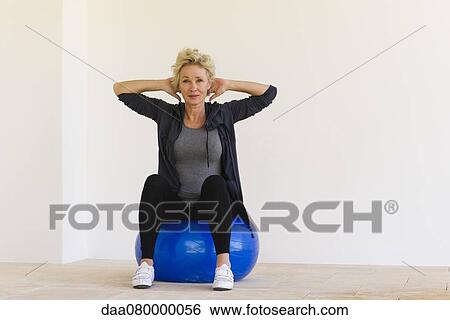 Mature woman sitting on fitness ball with hands behind head View Large Photo Image Stock Photograph - Mature woman sitting on fitness ball with hands behind head. Fotosearch