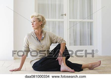 Mature woman sitting on floor doing spinal twist View Large Photo Image Picture - Mature woman sitting on floor doing spinal twist. Fotosearch