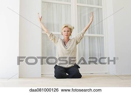 Mature woman sitting on heels with arms raised View Large Photo Image Stock Photograph - Mature woman sitting on heels with arms raised. Fotosearch
