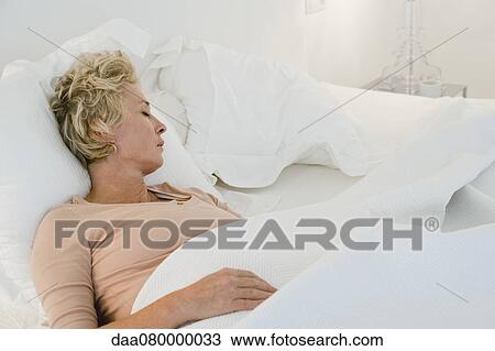 Stock Image - Mature woman sleeping in bed. Fotosearch