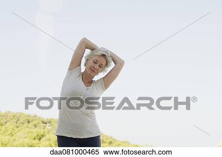 Stock Photography - Mature woman stretching with eyes closed. Fotosearch