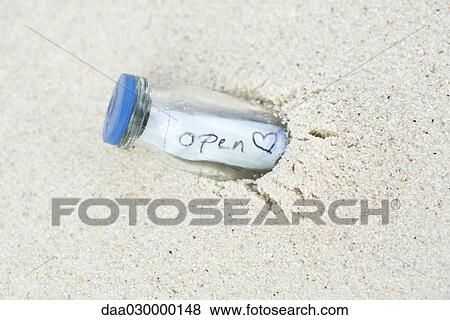 Message in a bottle, half buried in sand View Large Photo Image Stock Photo - Message in a bottle, half buried in sand. Fotosearch