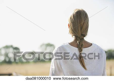 Mid-adult woman looking into distance at field, rear view View Large Photo Image Stock Image - Mid-adult woman looking into distance at field, rear view. Fotosearch