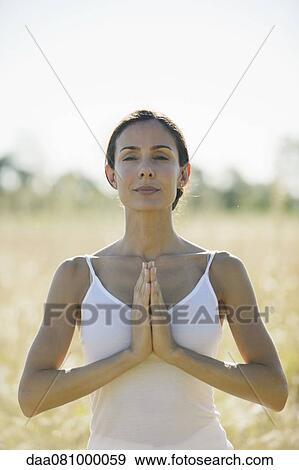 Stock Photo - Mid-adult woman meditating outdoors. Fotosearch