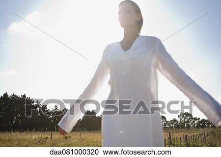 Mid-adult woman standing in field with eyes closed and arms outstretched View Large Photo Image Stock Image - Mid-adult woman standing in field with eyes closed and arms outstretched. Fotosearch