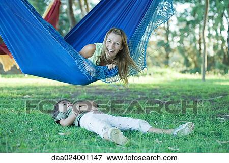 Mother and boy, woman lying in hammock while boy lies on grass View Large Photo Image Stock Photo - Mother and boy, woman lying in hammock while boy lies on grass. Fotosearch