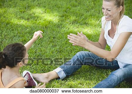 Stock Photo - Mother and daughter playing on grass. Fotosearch