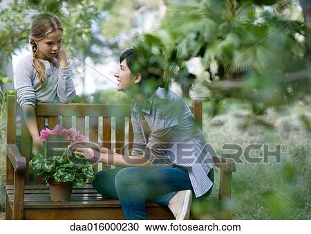 Stock Image - Mother and daughter tending potted plant. Fotosearch