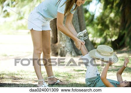 Stock Photo - Mother and son, boy lying on back, mother standing, holding his feet. Fotosearch