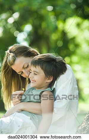 Mother and son, boy sitting on woman's lap, giggling View Large Photo Image Picture - Mother and son, boy sitting on woman's lap, giggling. Fotosearch