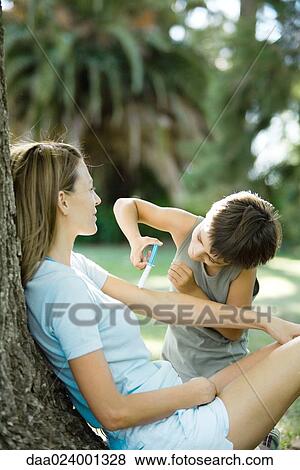 Mother and son outdoors, boy pretending to give woman shot View Large Photo Image Stock Photo - Mother and son outdoors, boy pretending to give woman shot. Fotosearch