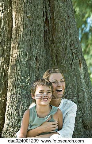 Mother and son, sitting at base of tree, laughing View Large Photo Image Stock Photo - Mother and son, sitting at base of tree, laughing. Fotosearch