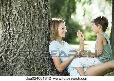 Mother and son sitting outdoors, playing together View Large Photo Image Stock Image - Mother and son sitting outdoors, playing together. Fotosearch
